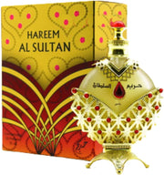 The Khadlaj Hareem Al Sultan Gold 35ml oil by Dubai Perfumes, featuring an ornate gold and red design, sits elegantly in front of its matching box as a concentrated, non-alcoholic fragrance.