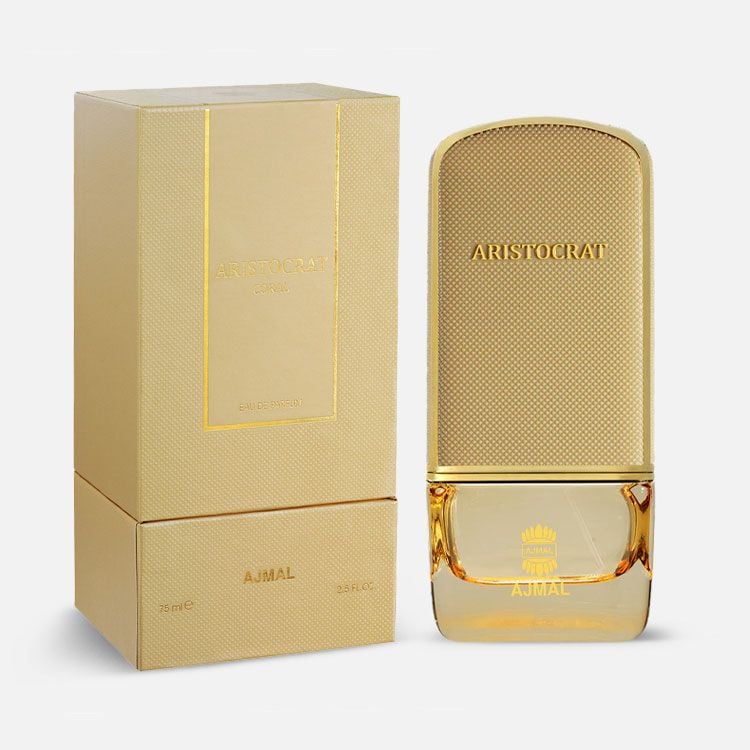 A gold-colored bottle of Rio Perfumes Ajmal Aristocrat Coral 75ml Eau De Parfum is displayed next to its matching gold box, showcasing a luxurious unisex fragrance.