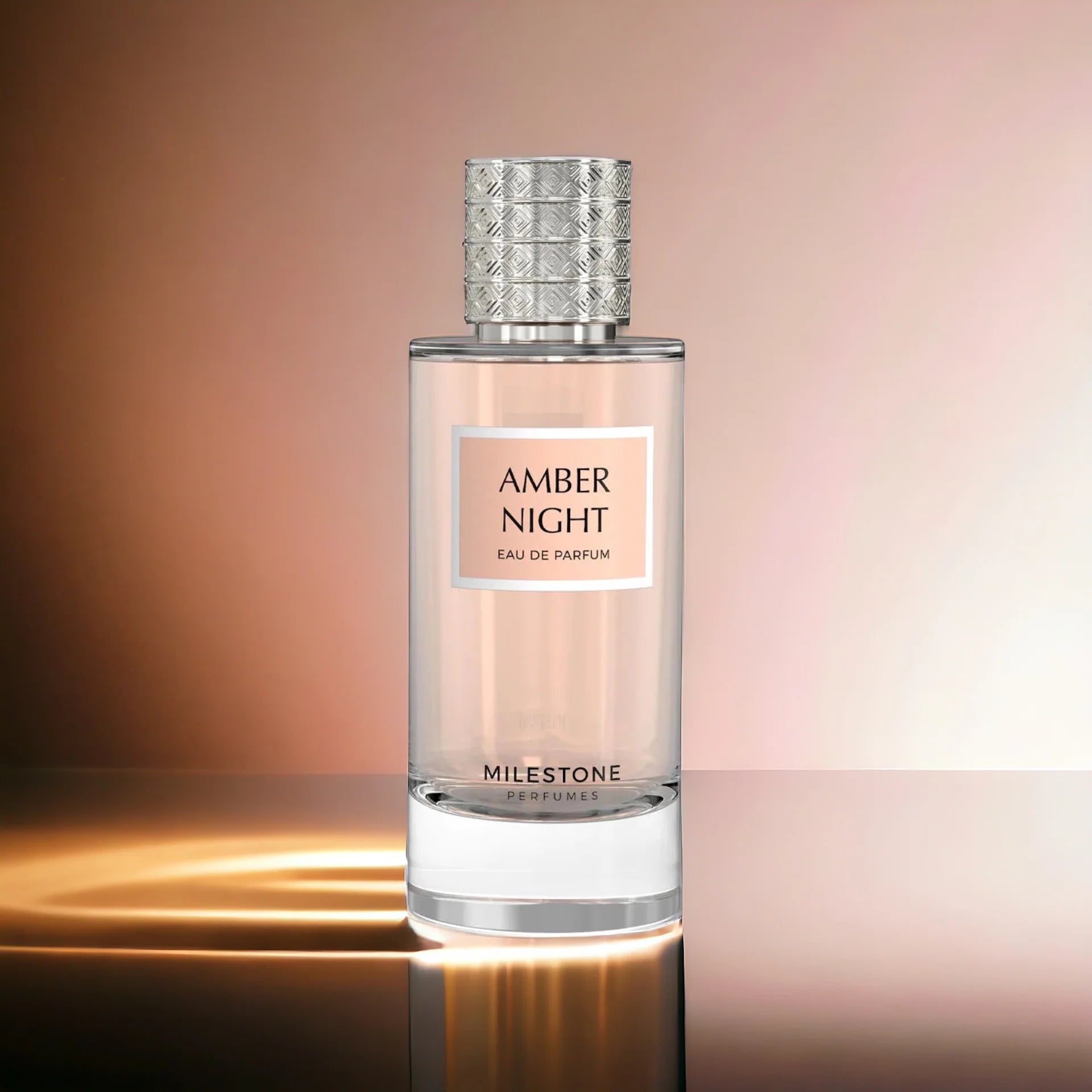 A bottle of "Milestone Amber Night" 85ml Eau de Parfum by Rio Perfumes, with a textured metallic cap and soft gradient background, carries notes of vanilla rose for an enchanting aroma.