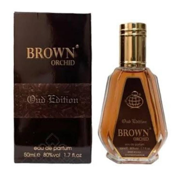 A bottle of Fragrance World Brown Orchid Oud Edition 50ml Eau De Parfum is elegantly displayed next to its sophisticated black and brown packaging box.