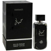 A black perfume bottle labeled "Fragrance World Hayaati 100ml Eau de Parfum" stands next to its matching box, exuding the sophisticated allure of an unisex woody cologne by Lattafa.