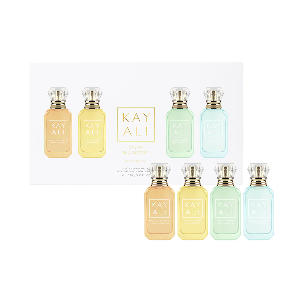 A travel-friendly fragrance set, the Kayali Vacay in a Bottle 4 x 10ml Miniature Set, includes four small colored perfume bottles with gold caps displayed in front of a white box labeled "KAYALI.