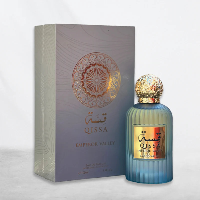 A blue Wadi Al Khaleej Qissah Emperor Valley 100ml Eau De Parfum bottle with a decorative golden cap sits next to its matching patterned box.