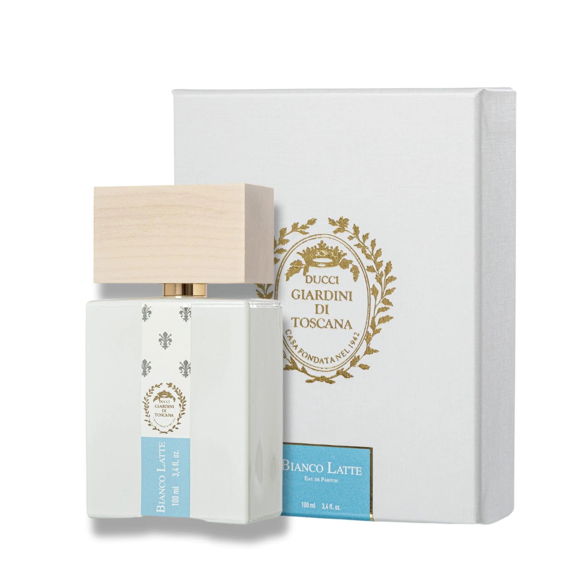 A white perfume bottle with a wooden cap labeled "Bianco Latte" stands in front of its white box with gold accents. The Giardini di Toscana Bianco Latte Eau De Parfum seduces with its Amber Vanilla fragrance, enriched by a hint of caramel sweetness.