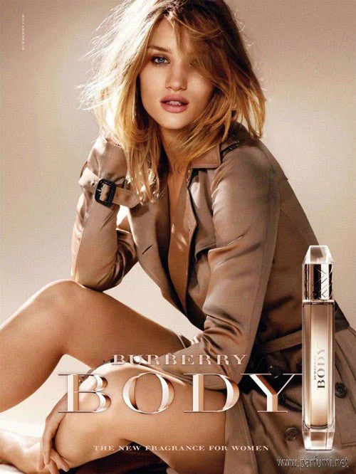 A woman in a tan coat sits gracefully next to a Burberry Body 85ml Eau De Parfum bottle, with "Burberry" text elegantly displayed on the image.