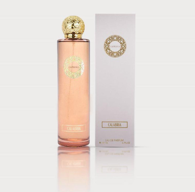 A tall, pink perfume bottle with a gold cap and label stands next to a matching white and gold box. The label reads "Capriole Calabria 200ml Eau De Parfum" and "Rio Perfumes." This Eau De Parfum exudes an exquisite fragrance that embodies elegance.