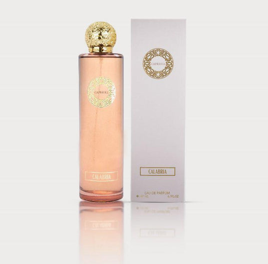 A tall, pink perfume bottle with a gold cap and label stands next to a matching white and gold box. The label reads 