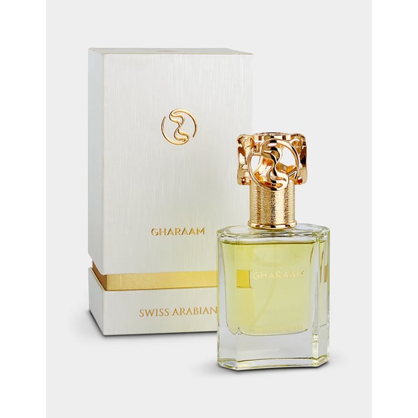 A bottle of Swiss Arabian Gharaam 50ml Eau De Parfum with a gold cap is placed in front of its matching white and gold box, presenting a sophisticated unisex fragrance.