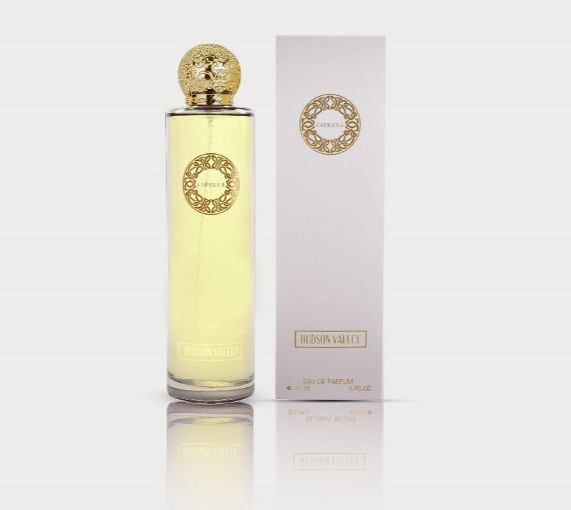 A bottle of Rio Perfumes Capriole Hudson Valley 200ml Eau De Parfum with a gold cap and ornate detailing, displayed next to its white box packaging. This warm spicy fragrance for men and women adds a touch of elegance to any collection.