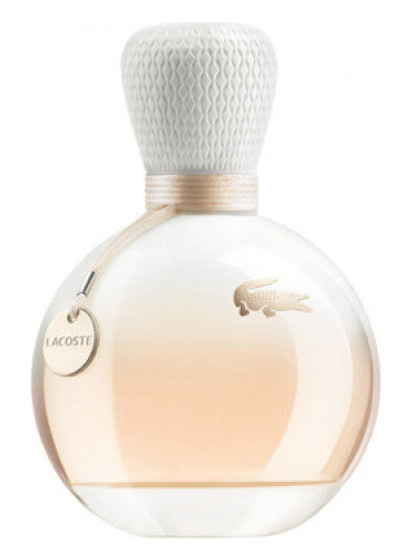 The Lacoste Eau de Lacoste Pour Femme 90ml Eau De Parfum is presented in a round bottle with a textured white cap, adorned with the Lacoste logo and a small tag. This elegant packaging perfectly captures the delightful Floral Fruity fragrance of the perfume.