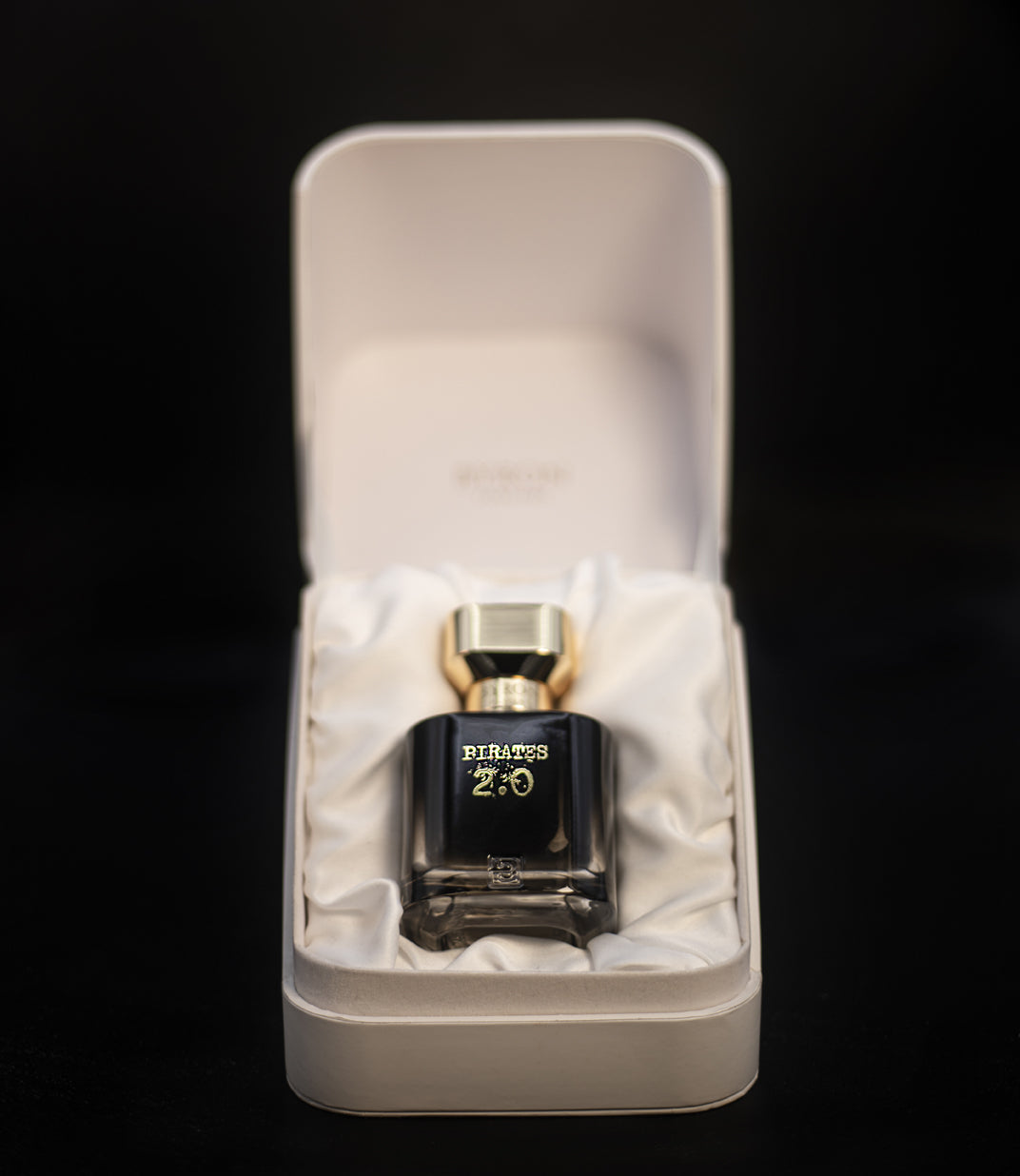 A bottle of Byron Parfums Pirates 2.0 Narcotic Collection 75ml Extrait De Parfum, elegantly packaged in a white box, resting on a sleek black surface.