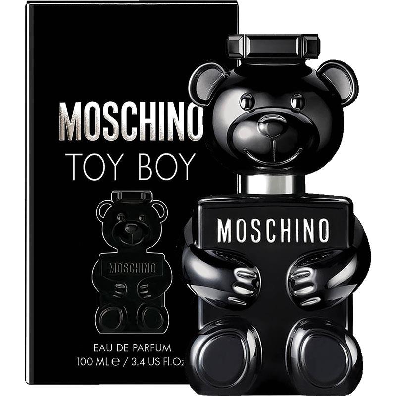 The Moschino Toy Boy 100ml Eau De Parfum bottle, designed in the delightful shape of a teddy bear, is displayed next to its corresponding box. This men's fragrance by Moschino emits a unique and captivating woody spicy aroma.